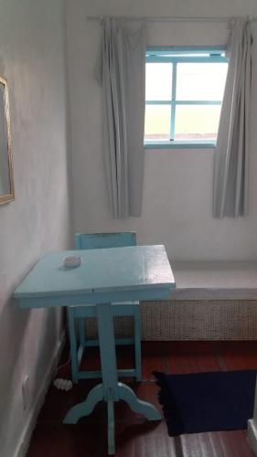 a blue table and a chair in a room with a window at Antonia Hospedaria 1 in Búzios