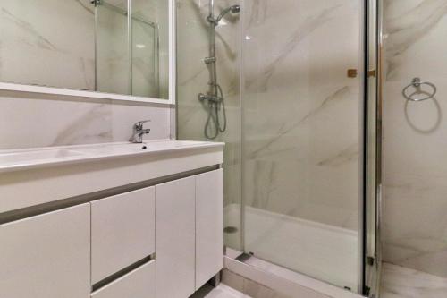 een witte badkamer met een douche en een wastafel bij Villa Fuseta 102 T in Fuzeta
