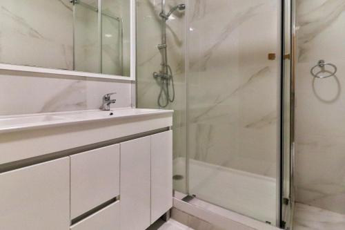 a white bathroom with a shower and a sink at Villa Fuseta 102 T in Fuzeta