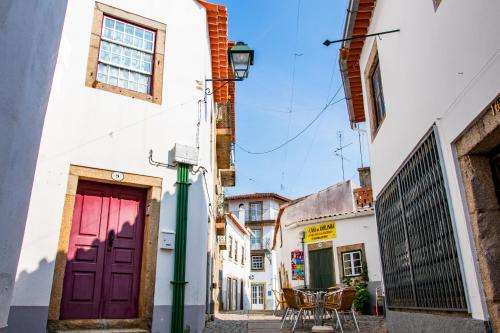 a street in an alley with a red door at Casa Sobreira da Silva - Alojamento Local in Almeida
