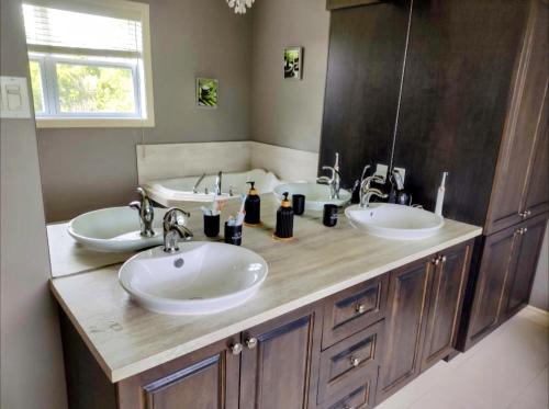 baño con 2 lavabos y espejo grande en Chalet chez Divine!, en Trois-Rivières