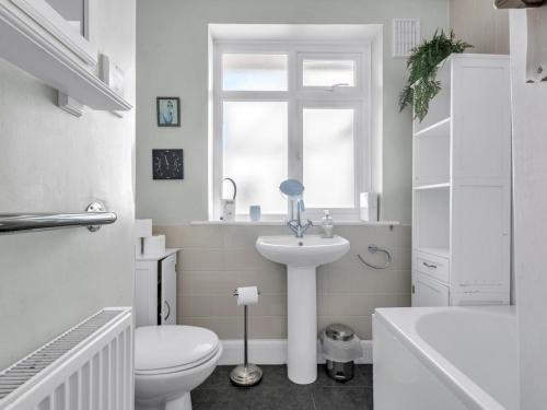 a white bathroom with a toilet and a sink at Pass the Keys Little Haven A stunning Bungalow in Minnis Bay in Birchington