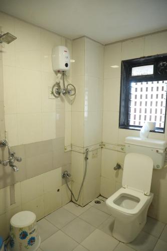 a white bathroom with a toilet and a window at Hotel Shiv Leela Grand in Mumbai