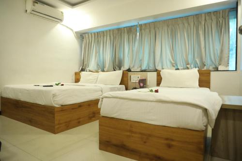 1 Schlafzimmer mit 2 Betten mit weißer Bettwäsche und einem Fenster in der Unterkunft Hotel Shiv Leela Grand in Mumbai