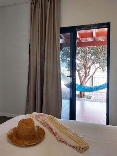 a straw hat sitting on a bed in front of a window at Oásis by BCA Villas in Porto Santo