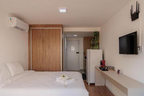 a bedroom with a white bed and a refrigerator at Studio encantador em Poços de Caldas-MG PGO209 in Poços de Caldas