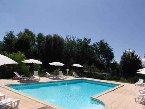 a swimming pool with chairs and umbrellas at Les Petits Prés in Vitrac