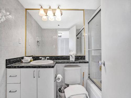 a bathroom with a toilet and a sink and a mirror at Beachfront Ocean View Condo Beach Service 520 in Miami Beach