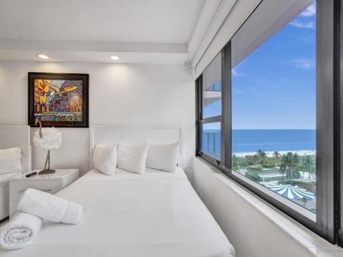 a bedroom with a white bed and a large window at Amazing Ocean View Condo Beach Service 1111 in Miami Beach