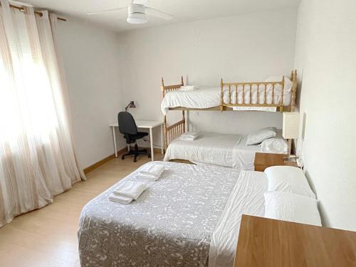 1 Schlafzimmer mit 2 Betten und einem Schreibtisch mit einem Computer in der Unterkunft Villa Flores in Navalcarnero