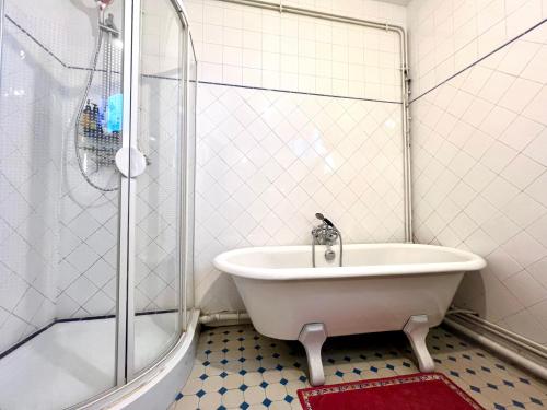 une salle de bain blanche avec une baignoire et une douche dans l'établissement Paris 2 bedrooms chic apartment 18th district, à Paris