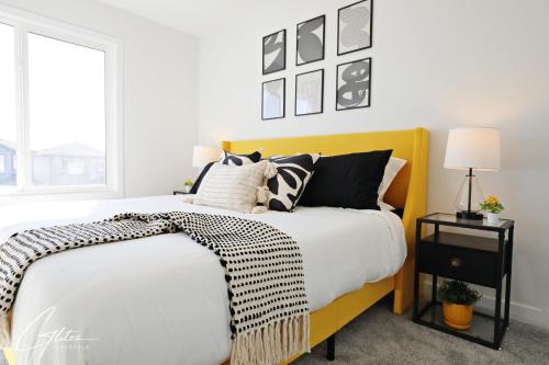 - une chambre avec un lit jaune et des oreillers noirs et blancs dans l'établissement Beautiful Home With 4 King Beds,Airport,Disney+, à Edmonton