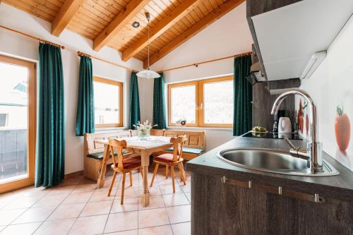 a kitchen with a sink and a table with chairs at Ferienwohnungen Badbruckerweg- Bad Gastein in Bad Gastein