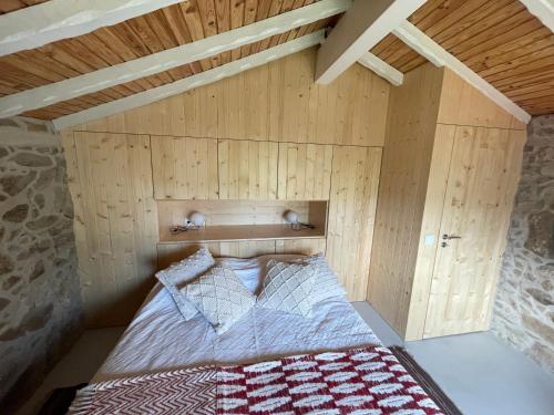 Bett in einem Zimmer mit einer Holzwand in der Unterkunft Casa Velha-SantiagoFamilyHouse in Sever do Vouga