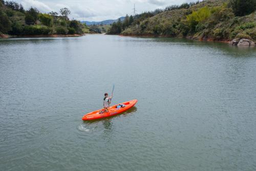 a person in an orange kayak on a river at Glamping Montecarlo Lodge Cubo de Madera-Guatapé in Guatapé