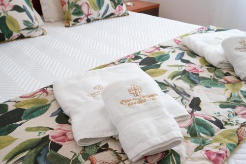 a bed with white towels with flowers on it at Casa Petisqueira 88-Paredes-Oporto in Rebordosa