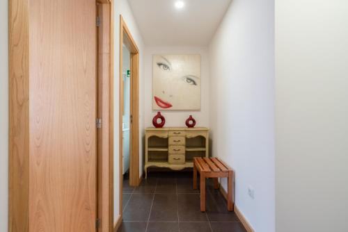a hallway with a table and a picture of a woman at Casa Petisqueira 88-Paredes-Oporto in Rebordosa