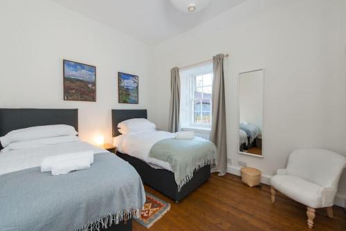 a bedroom with two beds and a chair and a window at Stunning Stables Cottage in East Lothian Country Estate in North Berwick