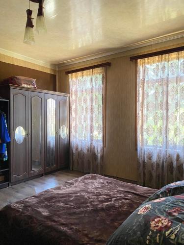 um quarto com uma cama, uma cómoda e janelas em anno's house em Zugdidi