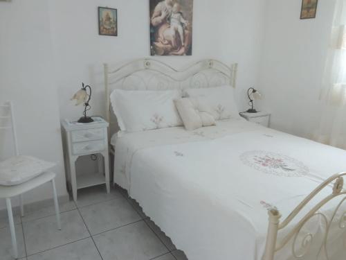 a white bedroom with a white bed and a table at Casa Mary in Lavello