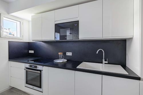 a white kitchen with a sink and a microwave at Beautiful renovated 4P1BR apartment with view on garden in Antibes