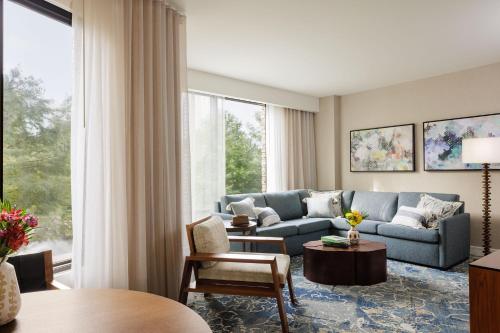 a living room with a blue couch and a large window at The Woodlands Resort, Curio Collection by Hilton in The Woodlands