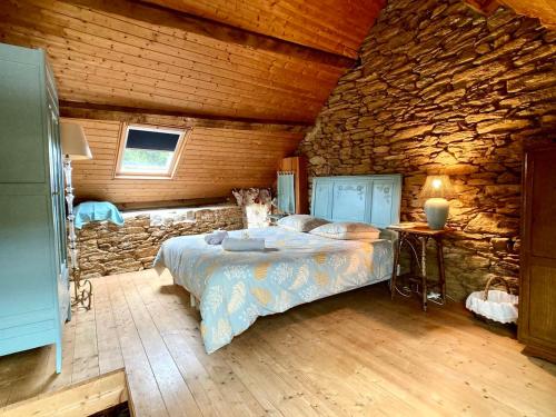 a bedroom with a bed and a stone wall at Penty LEGONA, authentique et chaleureux, 2-6 pers in Moëlan-sur-Mer