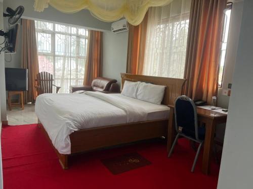Schlafzimmer mit einem Bett, einem Schreibtisch und Fenstern in der Unterkunft WAWA HOTEL in Turiani