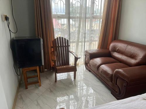 ein Wohnzimmer mit einem Sofa und einem TV in der Unterkunft WAWA HOTEL in Turiani