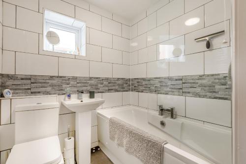 a white bathroom with a tub and a sink at Keeling in Exmouth