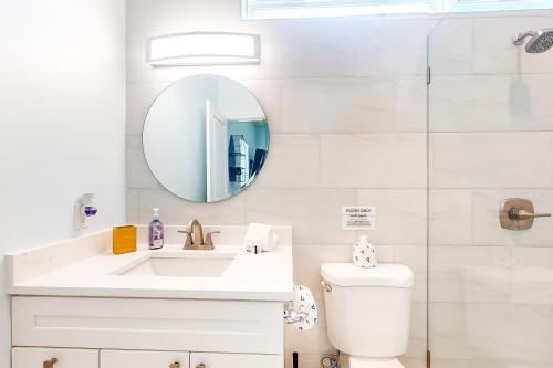 een witte badkamer met een wastafel en een spiegel bij The Blue Heron Cottage in St. Augustine
