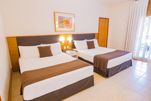 a hotel room with two beds and a window at Hotel JP Ribeirão Preto Resort & Convenções by Nacional Inn in Ribeirão Preto