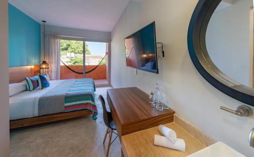 a bedroom with a bed and a mirror and a table at Sayulinda Hotel in Sayulita
