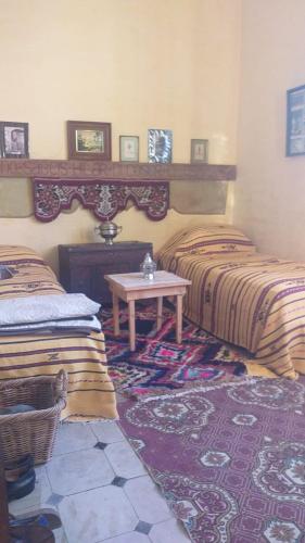 a bedroom with two beds and a table in it at La Maison Haute Larache Morocco in Larache