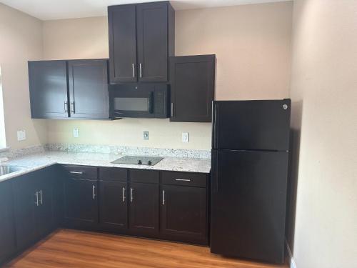 a kitchen with black cabinets and a black refrigerator at Palace Inn 290 & Jones Rd in Houston