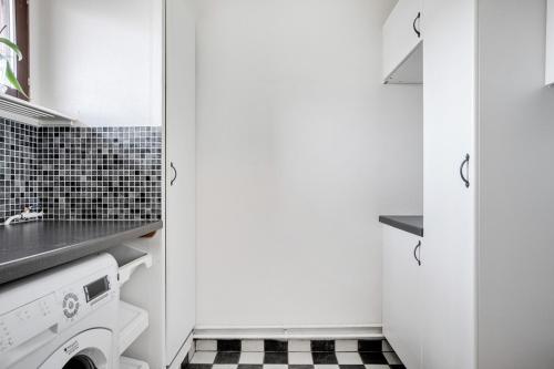 een witte keuken met een zwart-witte tegelvloer bij very comfortable room in a unique villa in Gävle