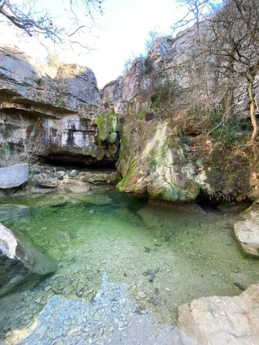 a pool of emerald green water next to a rocky cliff at Mas les jasses Chambre d'hôte calme et agréable à la campagne in Ferrières-les-Verreries