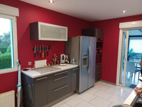 cocina con paredes rojas y electrodomésticos de acero inoxidable en Chez phiphi, en Ernée
