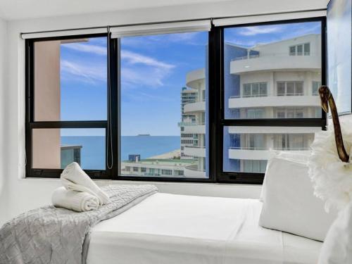 een wit bed in een kamer met een groot raam bij Ocean View Retreat Beach Service 1603 in Miami Beach