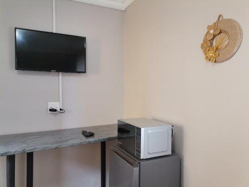 a counter with a microwave and a tv on a wall at Izibusiso Guest room in East London
