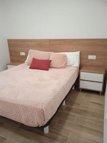 a bed with a red pillow on top of it at La casa del Timón.Planta baja in Muros