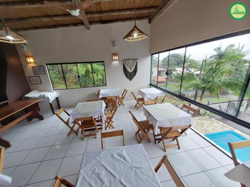 un restaurante con mesas y sillas y una piscina en Pousada Arthemis, en Garopaba