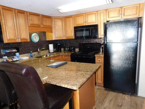 a kitchen with a black refrigerator and wooden cabinets at Condo Daytona Beach in Daytona Beach Shores