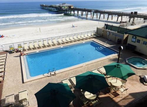 a swimming pool next to a beach and a pier at Condo Daytona Beach in Daytona Beach Shores