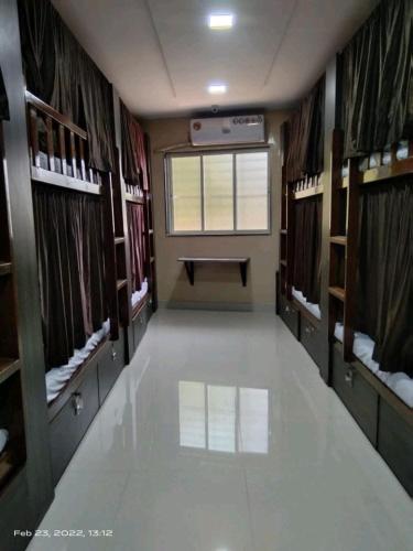 a large empty room with a window and a room with shelves at Marol dormitory in Mumbai