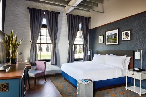 a hotel room with a large bed and windows at The Confluence Hotel in Hastings