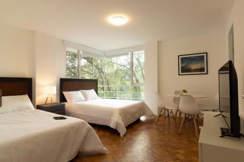 a hotel room with two beds and a television at Balsas By HomiRent in Mexico City