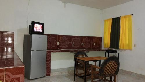 uma cozinha com uma mesa, um frigorífico e uma televisão em Departamento en la 43 em Oxkutzcab