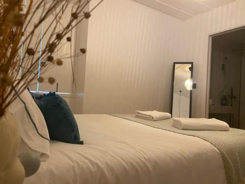 a white bed with a blue pillow and a mirror at Grândola Suites - Suite Henrique in Grândola