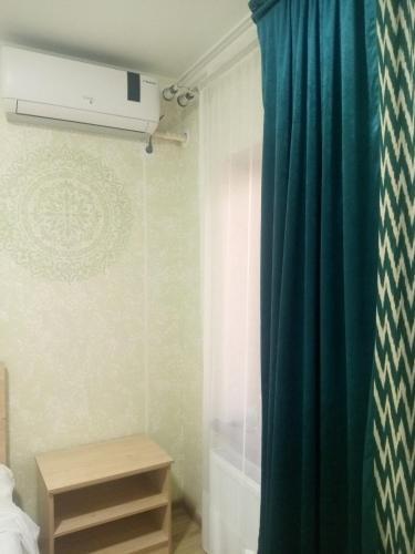 a bathroom with a green shower curtain and a table at Elita House Samarkand in Samarkand